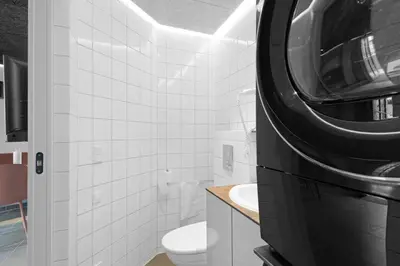 a bathroom with a toilet and a washer and dryer at Funart 12 in Pandrup