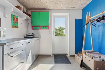 a kitchen with blue and green cabinets and a door at Spacious Holiday Home With Views Over Limfjorden in Jørsby