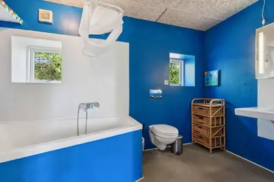 a blue bathroom with a toilet and a bath tub at Spacious Holiday Home With Views Over Limfjorden in Jørsby