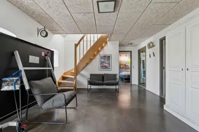 a living room with a staircase and a chair at Spacious Holiday Home With Views Over Limfjorden in Jørsby