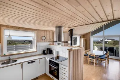 a kitchen with white cabinets and a table and a dining room at 4 bedrooms and a beautiful view in Vinderup