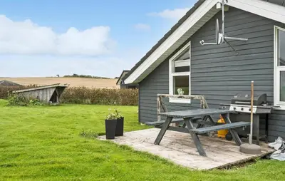 a picnic table and a grill outside of a house at Cozy Home In Lemvig With Sauna in Lemvig