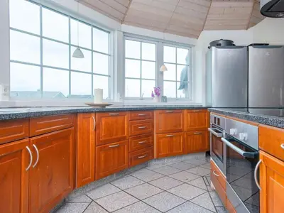 a large kitchen with wooden cabinets and windows at Luxury Beach Retreat - By Traum Ferienwohnungen in Harboør
