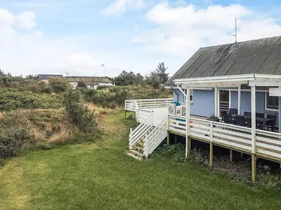 a blue house with a white porch and a yard at Seaside Escape with Views - By Traum Ferienwohnungen in Vestervig