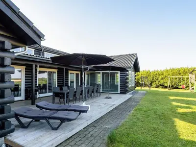 a patio with chairs and umbrellas on a house at Luxury Lodge with Limfjord View - By Traum Ferienwohnungen in Spottrup