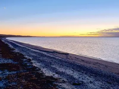 a beach with the sun setting in the distance at Family Beach Retreat - By Traum Ferienwohnungen in Løgstør