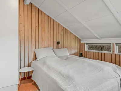 a bedroom with a large bed in a wooden wall at Holiday Home Wilmer - 600m from the sea by Interhome in Løkken
