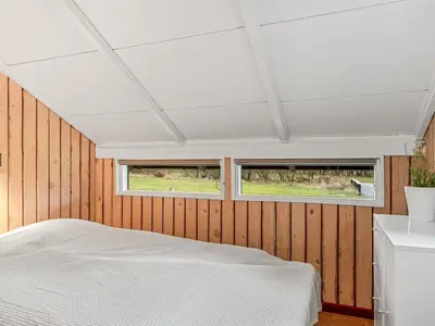 a bedroom with a white bed in a wooden wall at Holiday Home Wilmer - 600m from the sea by Interhome in Løkken