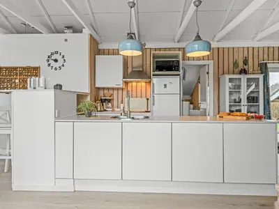 a kitchen with white cabinets and blue pendant lights at Holiday Home Wilmer - 600m from the sea by Interhome in Løkken
