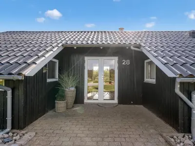 a black house with a white door and a roof at Holiday Home Wilmer - 600m from the sea by Interhome in Løkken
