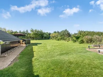 a large grassy field next to a building at Holiday Home Wilmer - 600m from the sea by Interhome in Løkken