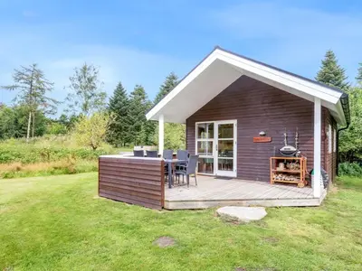 a small cabin with a deck in a yard at Holiday Home Unge - 2-9km from the sea by Interhome in Blokhus