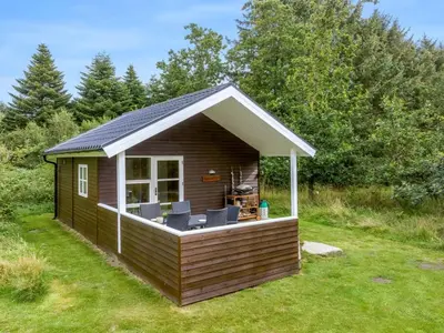 a cabin with a deck in the grass at Holiday Home Unge - 2-9km from the sea by Interhome in Blokhus