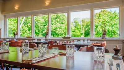 a dining room with tables and chairs and windows at Morup Mølle Kro in Bedsted Thy