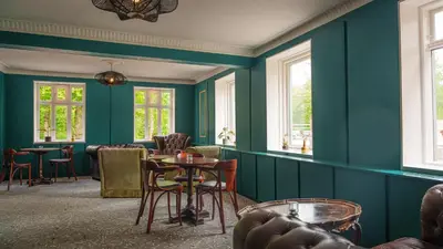 a green room with chairs and tables and windows at Morup Mølle Kro in Bedsted Thy