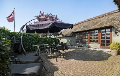 a patio with a table and chairs and an umbrella at 3 Bedroom Stunning Home In Farsø in Farsø