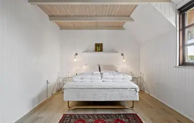 a white bedroom with a bed with a red rug at 3 Bedroom Stunning Home In Farsø in Farsø