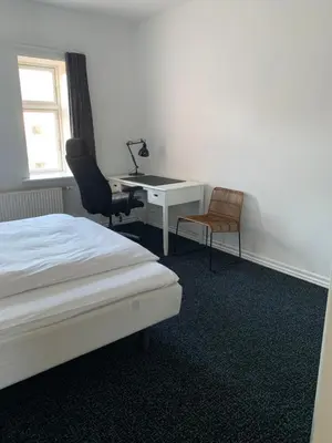 a bedroom with a bed and a desk and a chair at B&B Phønix in Holstebro