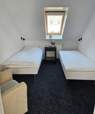 a room with two beds and a chair and a window at B&B Phønix in Holstebro