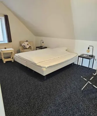 a bedroom with a white bed and a chair at B&B Phønix in Holstebro