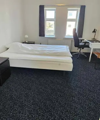a bed in a room with a desk and a chair at B&B Phønix in Holstebro