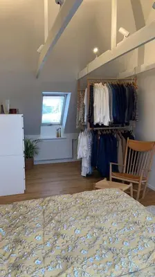 a bedroom with a bed and a rack of clothes at Rækkehus tæt på skov, sø og by in Viborg