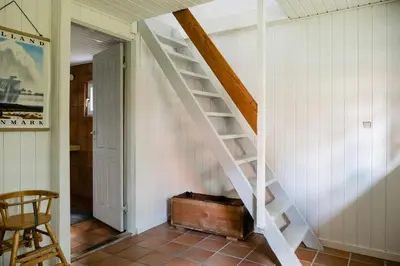 a white staircase in a room with a suitcase at Summer House For The Big Family Close To The Fjord in Agger