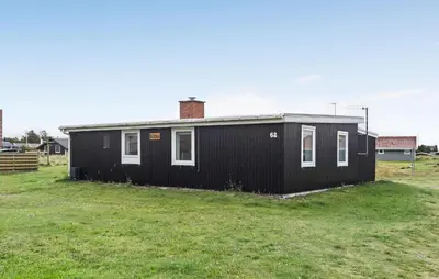 a black house sitting in a grassy field at 2 Bedroom Nice Home In Thisted in Thisted