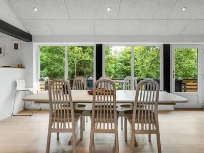 a dining room with a table and chairs and windows at Holiday Home Vicente - 14km to the fjord by Interhome in Års