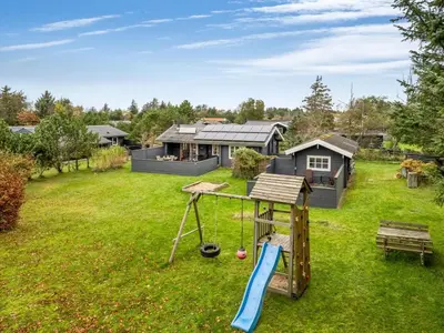 a yard with a playground and a house at Holiday Home Tammo - 1-1km from the sea by Interhome in Blokhus