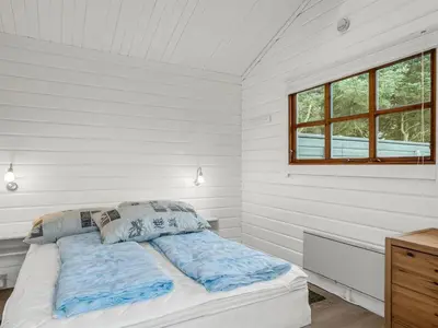 a white bedroom with a bed and a window at Holiday Home Tammo - 1-1km from the sea by Interhome in Blokhus