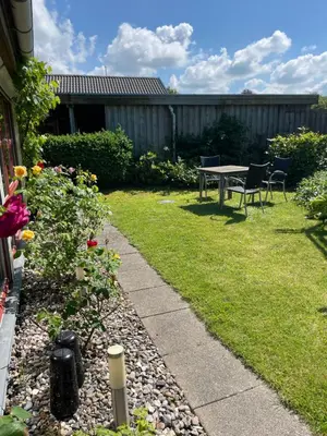 a backyard with a table and chairs and flowers at Naturlig Ro in Aalborg