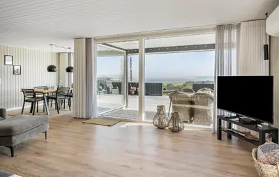 a living room with a flat screen tv and a table with chairs at Cozy Home In Lemvig With Wifi in Lemvig
