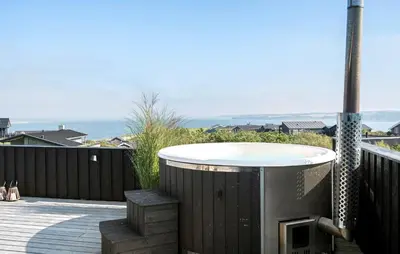 a hot tub on a deck with the ocean in the background at Cozy Home In Lemvig With Wifi in Lemvig