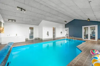a large swimming pool with blue water in a room at Pool And Activity House With A 180-Degree View Of The North Sea, Located At Lild Strand in Frøstrup