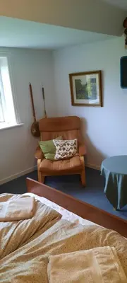 a bedroom with a couch and a chair in it at Dybvad Mølle bed and breakfast in Års