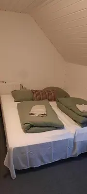 a large white bed with green pillows on it at Dybvad Mølle bed and breakfast in Års