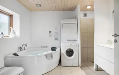 a white bathroom with a washing machine and a washer at Gorgeous Home In Blokhus With Sauna in Blokhus