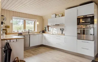 a kitchen with white appliances and a wooden ceiling at Gorgeous Home In Blokhus With Sauna in Blokhus