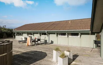 a house with a wooden deck with a table and chairs at Pet Friendly Home In Blokhus With Wifi in Blokhus