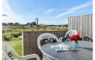 a table with chairs and a vase of flowers on a patio at Pet Friendly Home In Thisted With Sauna in Thisted