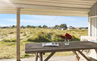 a wooden table with a vase of flowers on a porch at Pet Friendly Home In Thisted With Sauna in Thisted