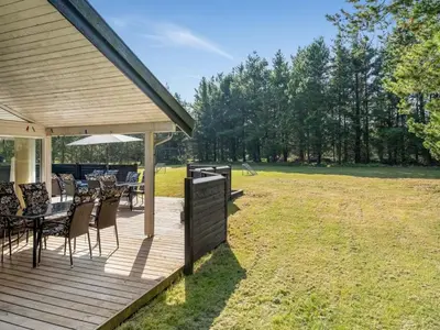 a wooden deck with tables and chairs on a field at Holiday Home Arild - 900m from the sea by Interhome in Saltum