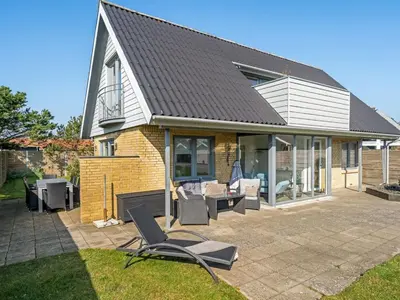 a house with a roof and chairs on a patio at Holiday Home Isabel - 600m from the sea by Interhome in Blokhus