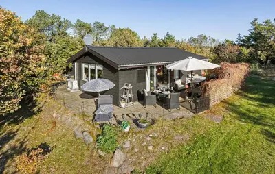 a small cabin with an umbrella and chairs at 2 Bedroom Nice Home In Løgstør in Løgstør