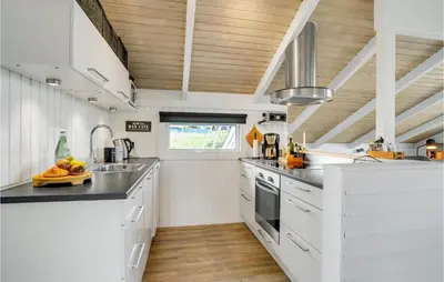 a kitchen with white cabinets and a wooden ceiling at Three-Bedroom Holiday Home Harboøre With A Fireplace 06 in Harboør