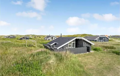 a house in a field with houses in the background at Three-Bedroom Holiday Home Harboøre With A Fireplace 06 in Harboør
