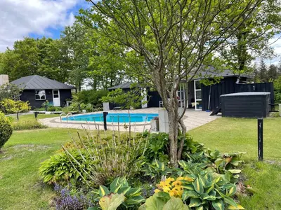 a garden with a tree and a swimming pool at Aneks i rolige omgivelser-adgang til pool og sauna in Avlum