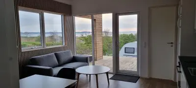 a living room with a couch and a table and windows at Premium hytte med udendørs spa in Farsø