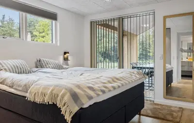 a bedroom with a large bed and a balcony at Cozy Home In Saltum With Sauna in Saltum
